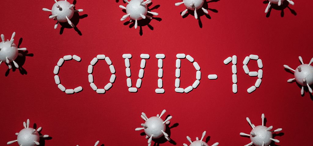 what we know now about coronavirus, image of red background with white pills spellign COVID-19 with 3d models.