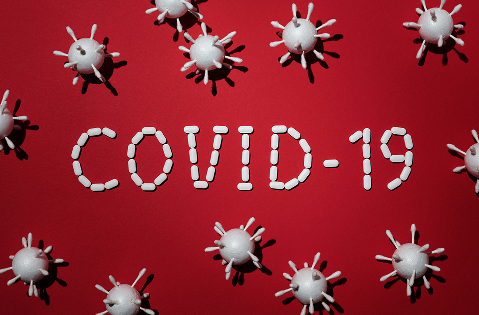 what we know now about coronavirus, image of red background with white pills spellign COVID-19 with 3d models.