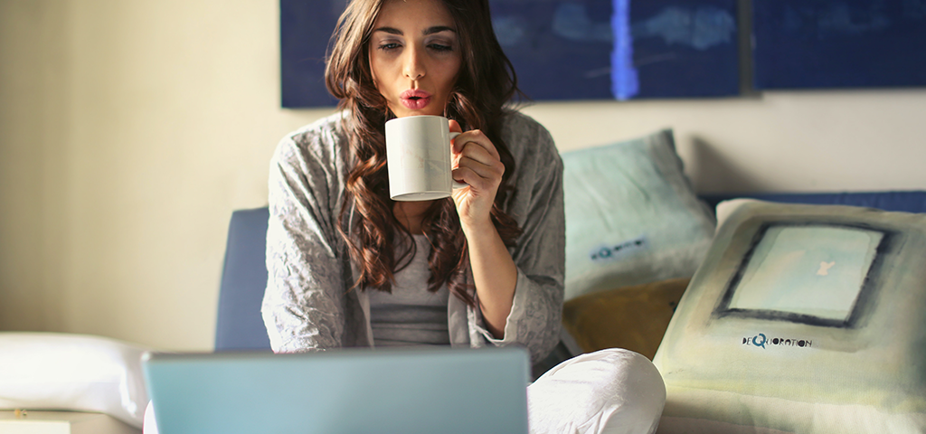 Mycotoxins: What Health Impact Can Your Daily Cup Of Coffee Have?, image of a woman drinking a cup of coffee on her bed.