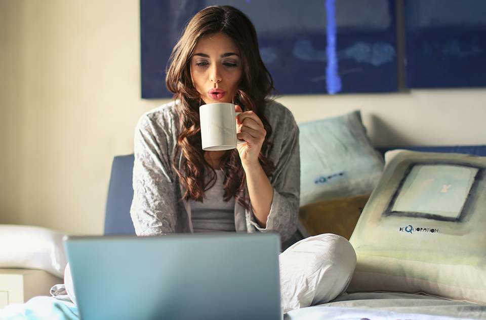 Mycotoxins: What Health Impact Can Your Daily Cup Of Coffee Have?, image of a woman drinking a cup of coffee on her bed.